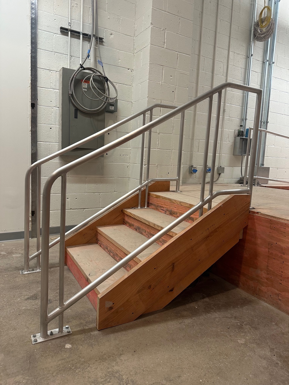 Two-rail metal stair railing anchored with welded base plates