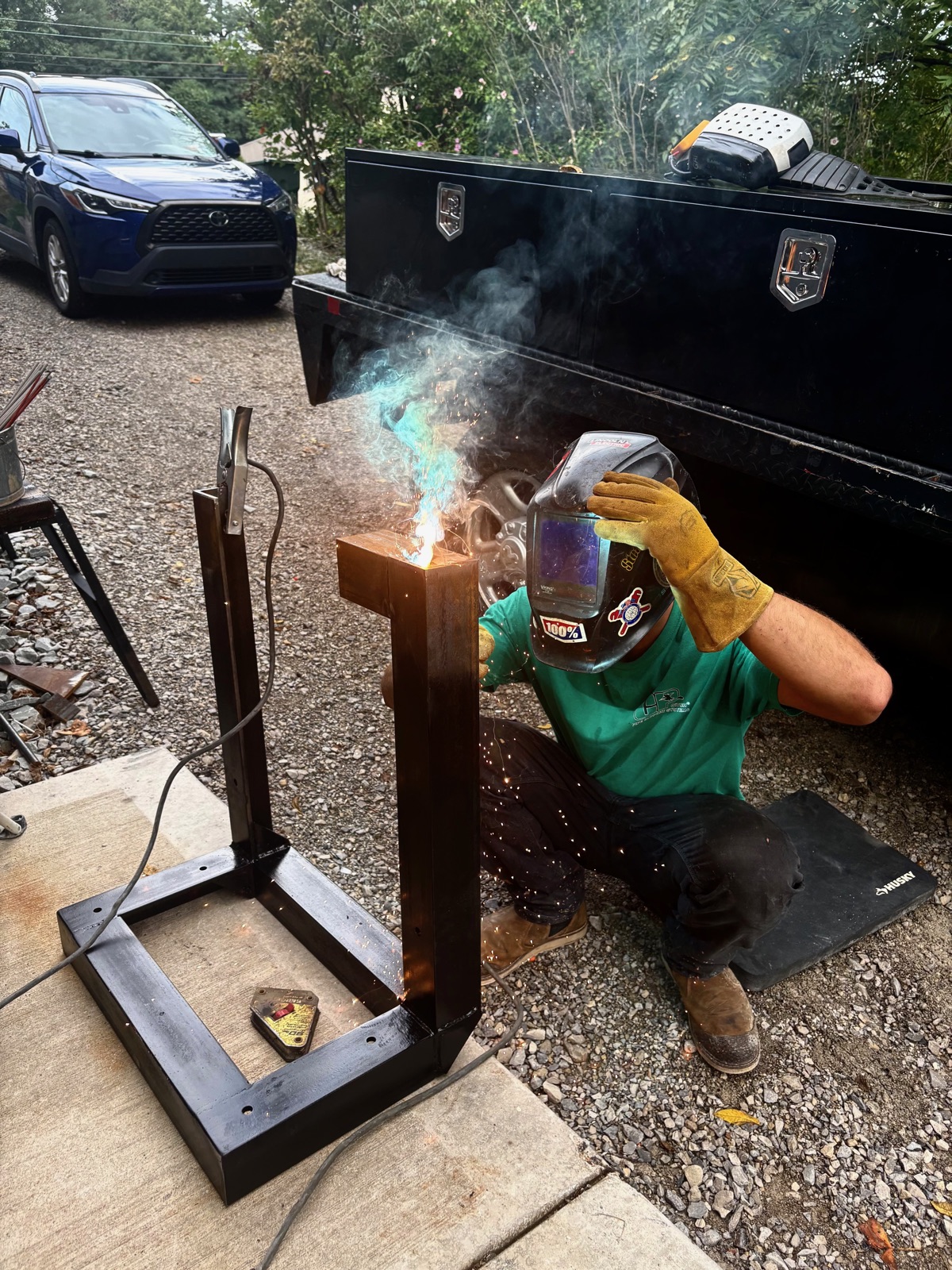 Welding an upright on a steel stand outdoors, sparks flying