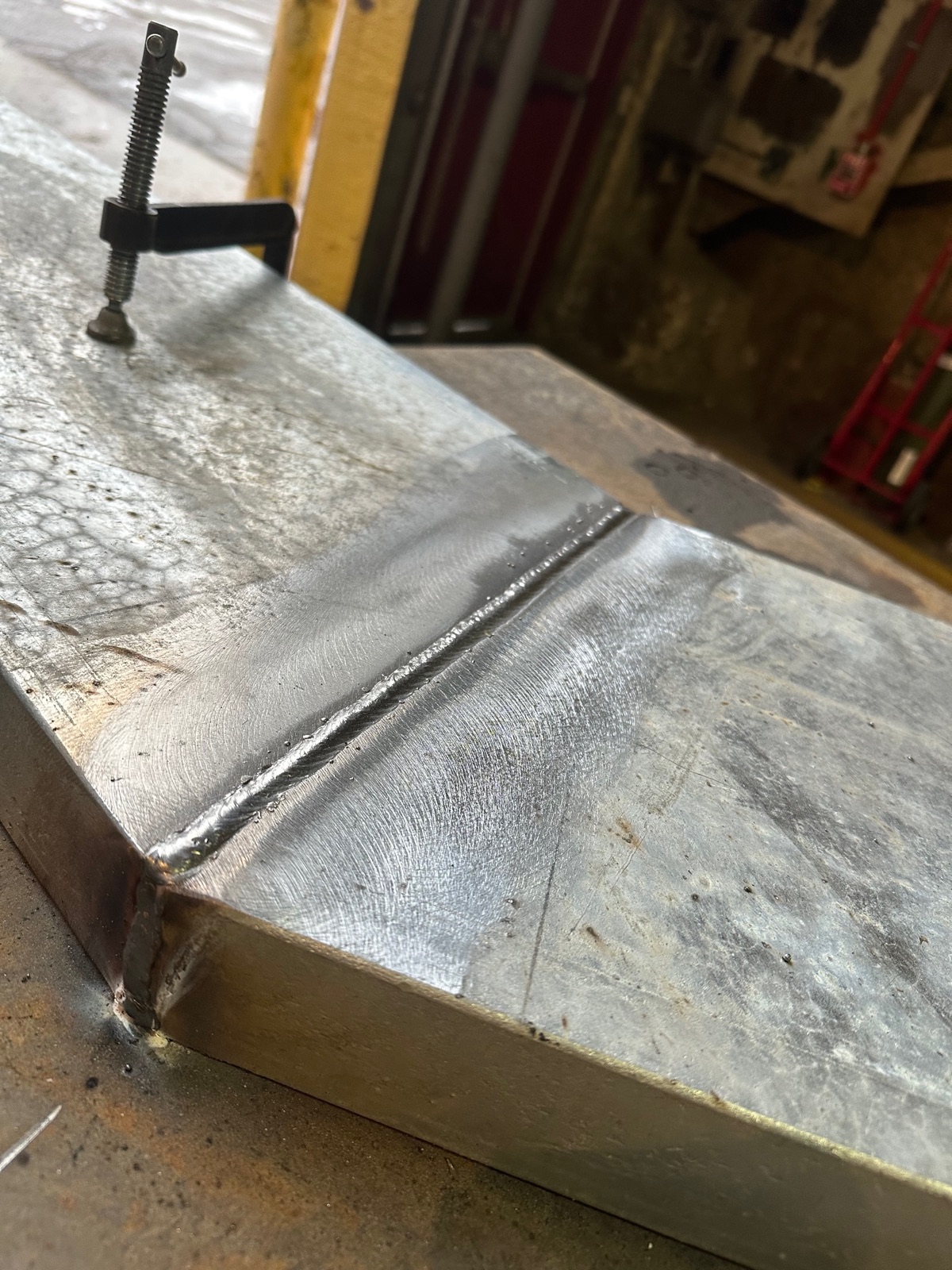 Fresh weld seam on heavy steel plate held with clamps